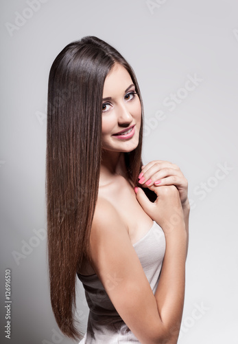 Beautiful young girl with long hair on a light background in the studio