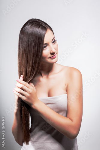 Beautiful young girl with long hair on a light background in the studio