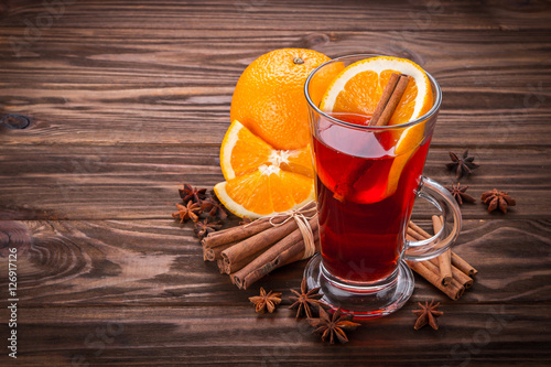 Glass with mulled wine, spices and fruits wooden background