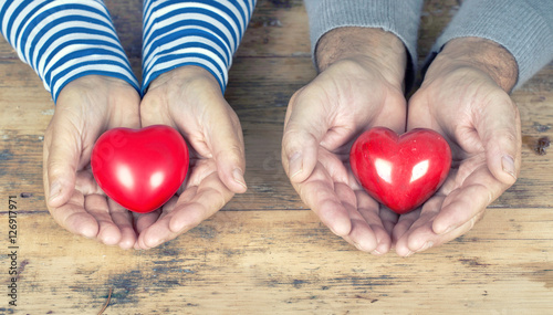 rote Herzen liegen in den Händen von Senioren