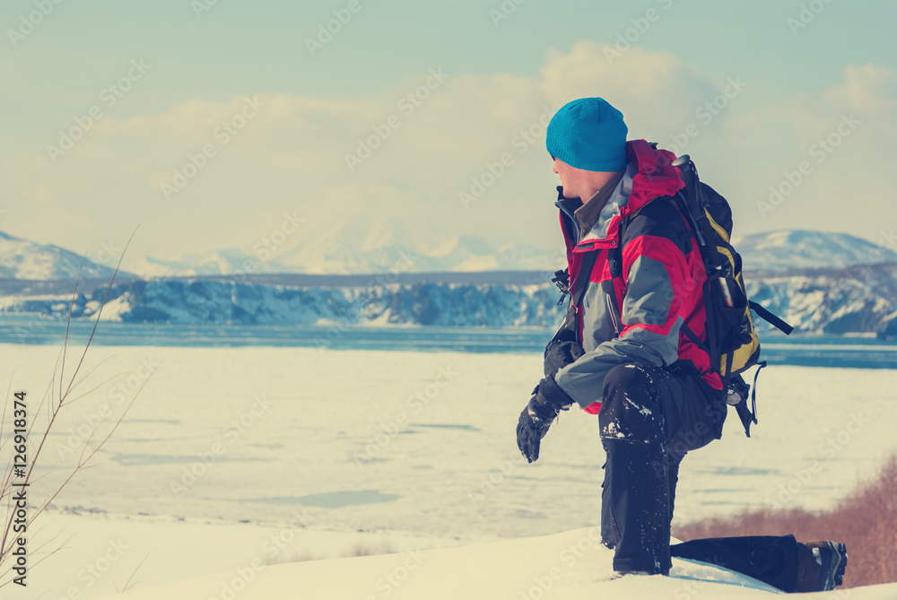 Hiker on the shore of bay covered with ice