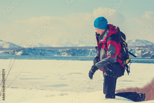 Hiker on the shore of bay covered with ice