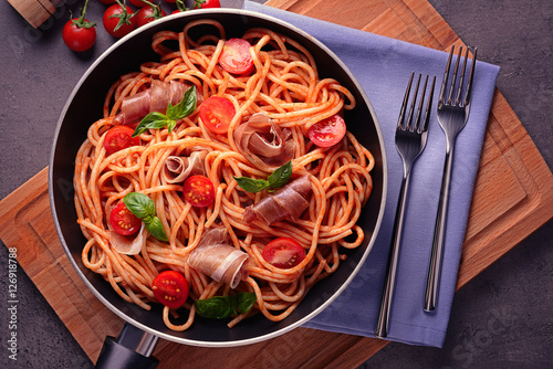 Spaghetti with amatriciana sauce and bacon in pan, top view