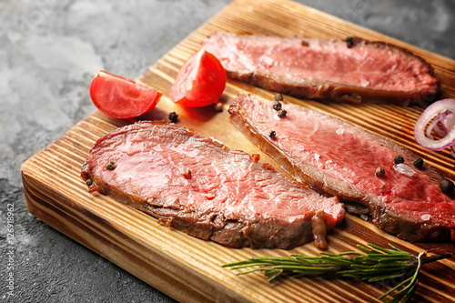 Delicious sliced steak with vegetables on board, closeup