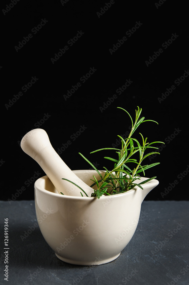 fresh rosemary in white ceramic mortar isolated on black with copy space. food photography