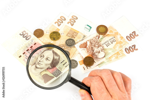 Czech money isolated on white background with hand holding magnifying glass