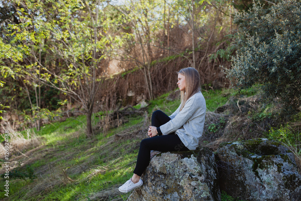 Young woman sitting on a big stone