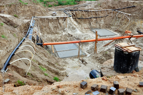 The process of lowering the groundwater level. Industrial sand quarry with water and a metal tube around it with thin tubes directed at the ground. photo