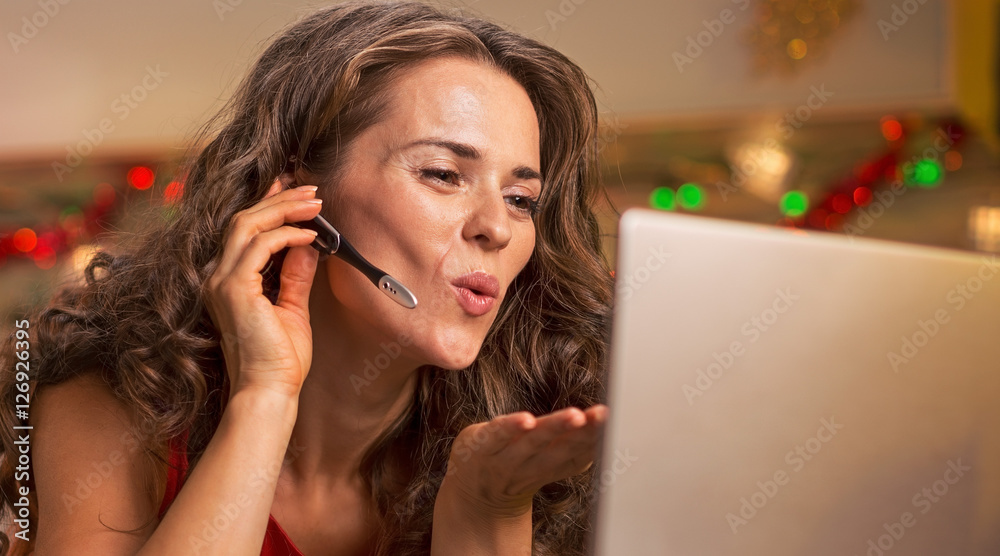 Happy young housewife in red dress having video chat on laptop i Happy young housewife in red dress having video chat on laptop i