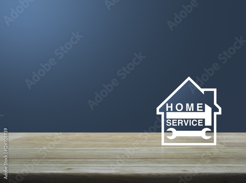 Hammer and wrench with house icon on wooden table over light blu