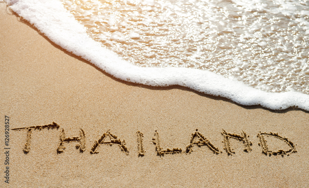 Fototapeta premium Thailand written on the sand beach near sea - travel holiday concept