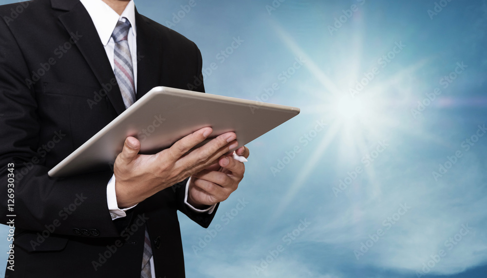 Businessman working on digital tablet, on blue sky with sunshine background Businessman working on digital tablet, on blue sky with sunshine background