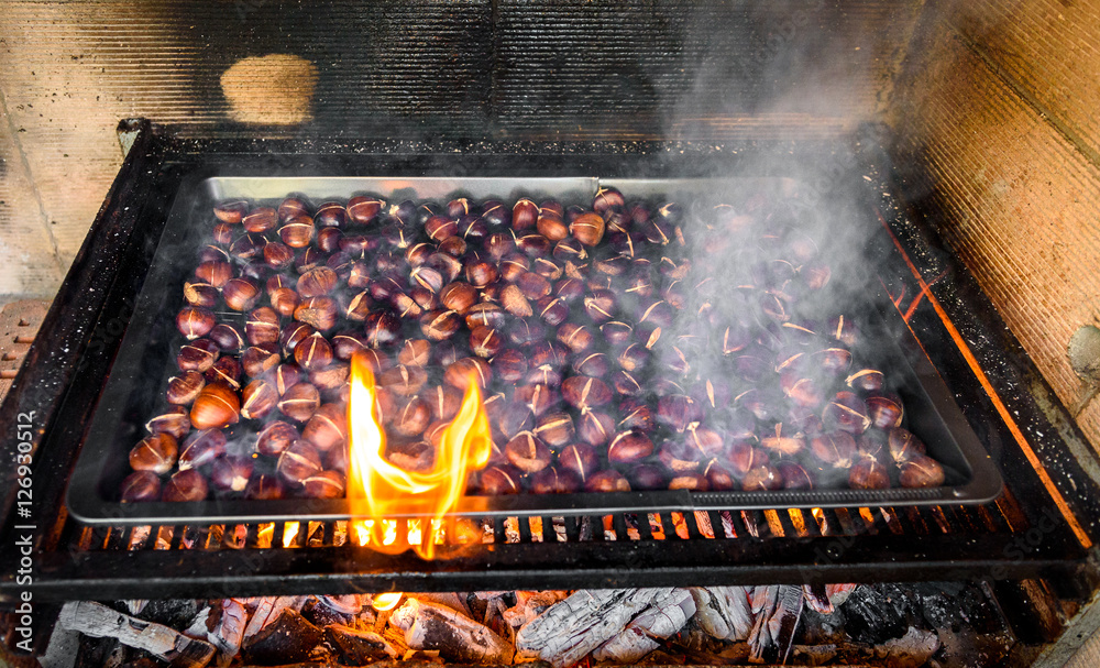 Roasting grilled Chestnuts on barbecue with flames, fire and cha Roasting grilled Chestnuts on barbecue with flames, fire and cha