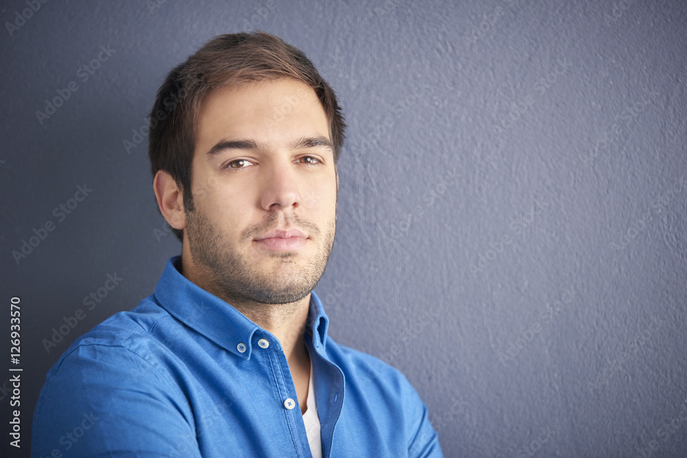 Young man portrait with copy space. Close-up shot of a handsome young man standing in front of a grey wall. Young man portrait with copy space. Close-up shot of a handsome young man standing in front of a grey wall.