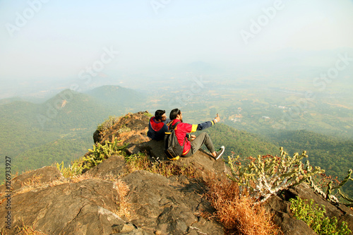 Two Young boys with backpack taking Selfie on the top of a mountain and enjoying valley view