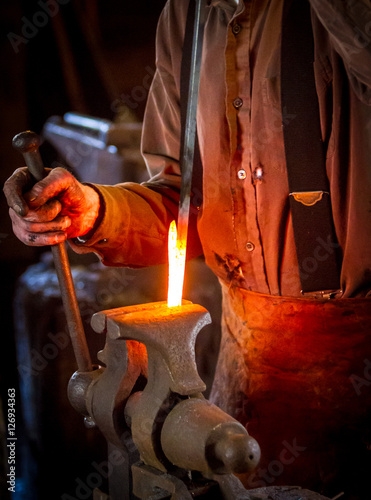 Blacksmith bending a hot metal rod