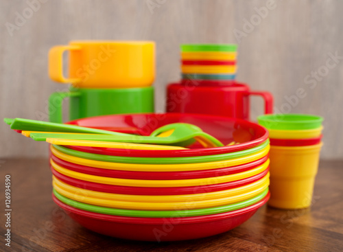 Посуда для пикника. Пластиковая посуда для пикника в комплекте. Разноцветные тарелки и кружки сложены стопкой.