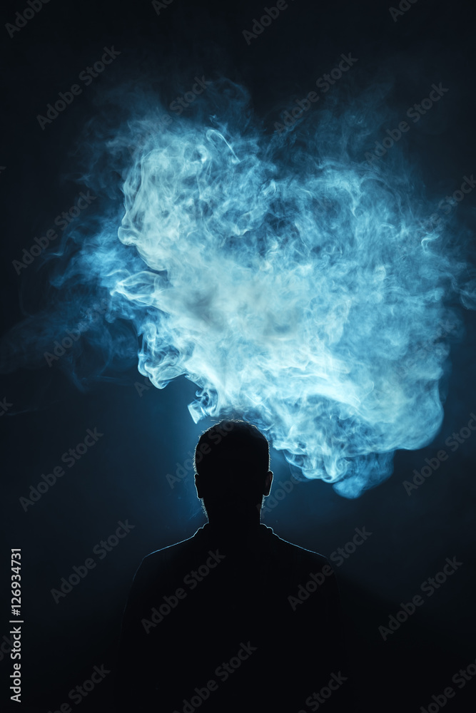 The man smoke a electronic cigarette against the background of the bright light