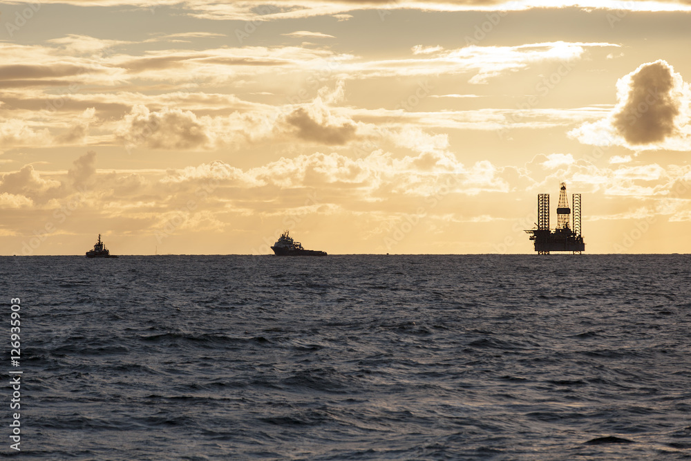 Silhouette of oil rig platform during sunset at oilfield