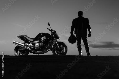 Obraz na płótnie Motorcyclist standing next to bike with helmet