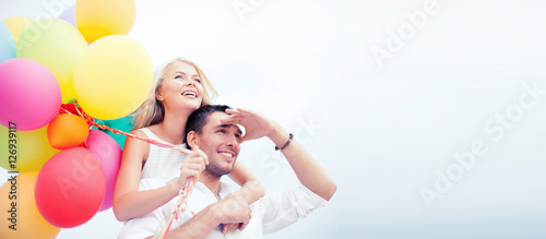 couple with colorful balloons at seaside