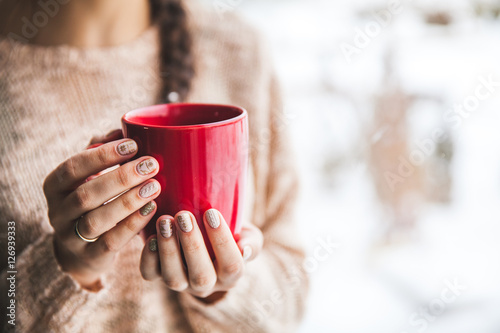 Woman's hand holding a red cup of coffee. With a beautiful winter manicure. Drink, fashion, morning