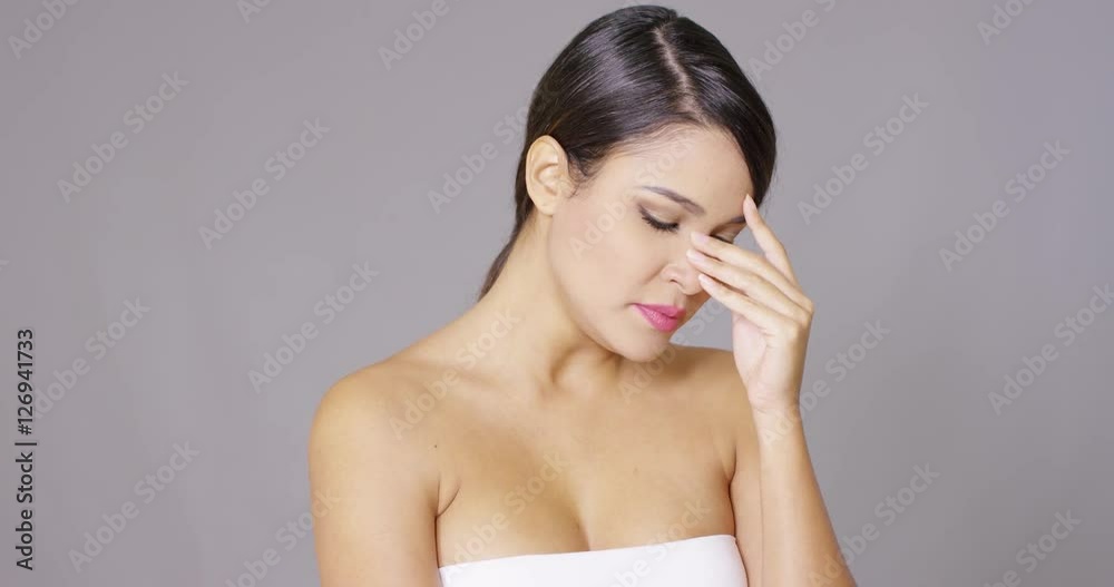 Sad young woman wiping a tear from her eye with a tissue head and shoulders isolated on grey Sad young woman wiping a tear from her eye with a tissue head and shoulders isolated on grey