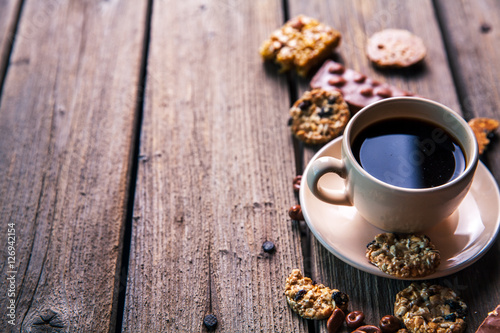 cup of coffee with a delicious chocolate and cookies on a wooden background