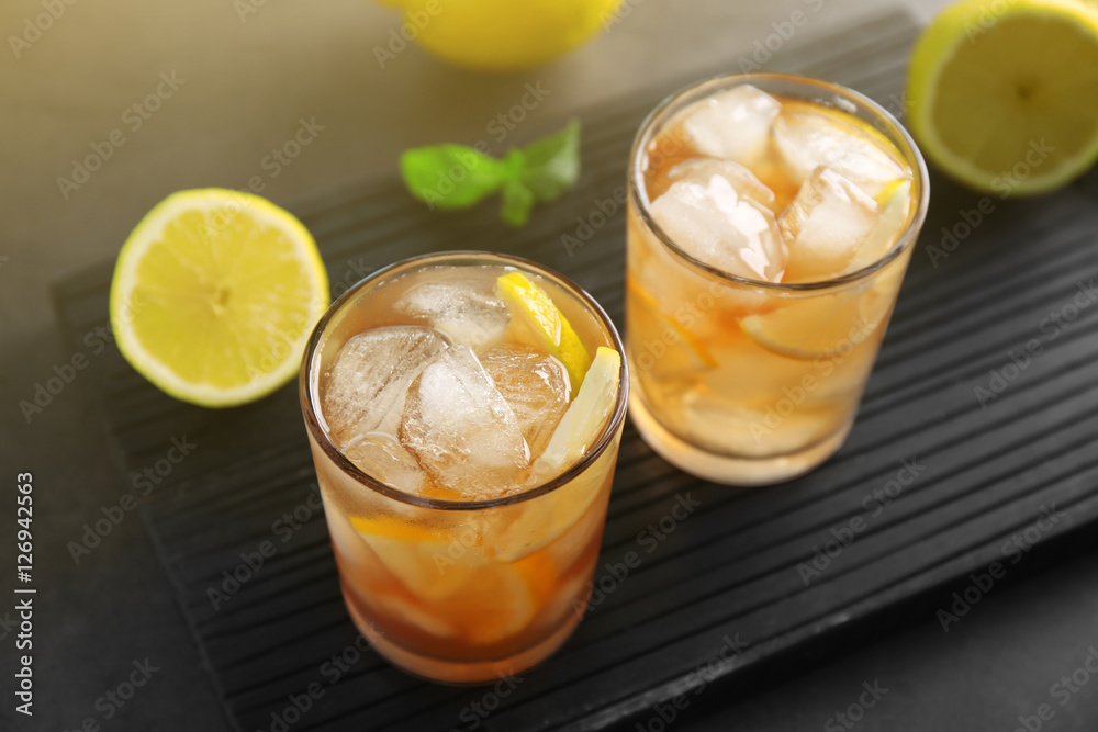 Glasses of iced tea with lemon slices on wooden cutting board Glasses of iced tea with lemon slices on wooden cutting board