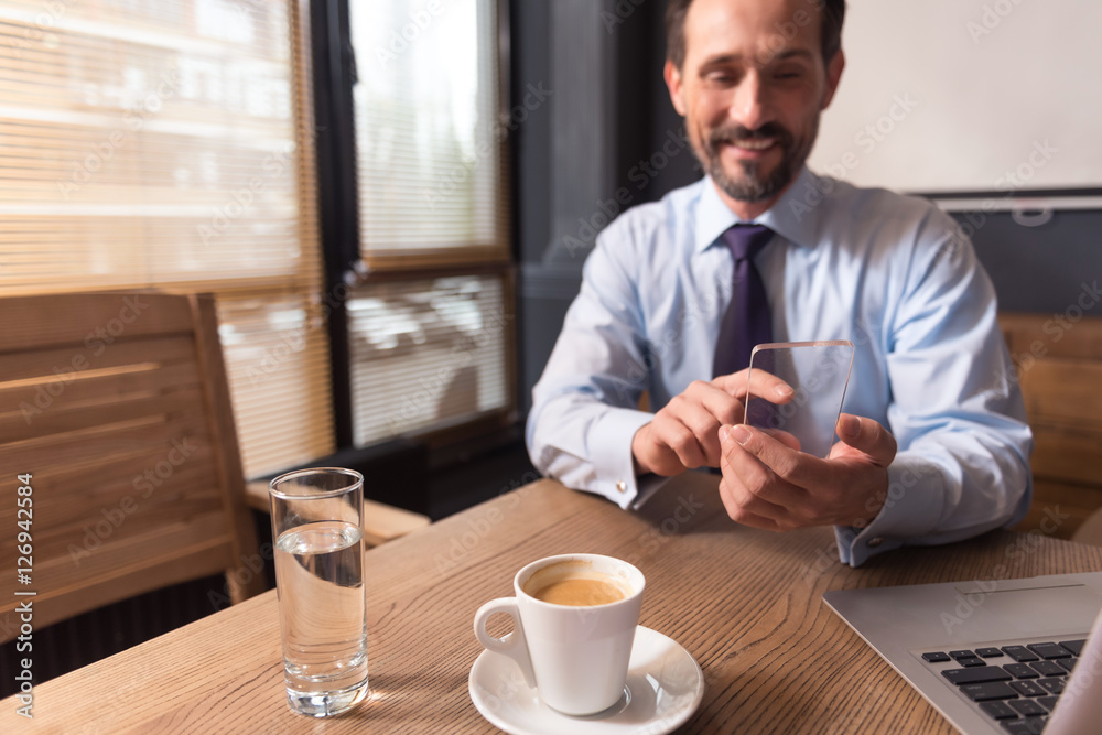 Happy positive man using an electronic device Happy positive man using an electronic device