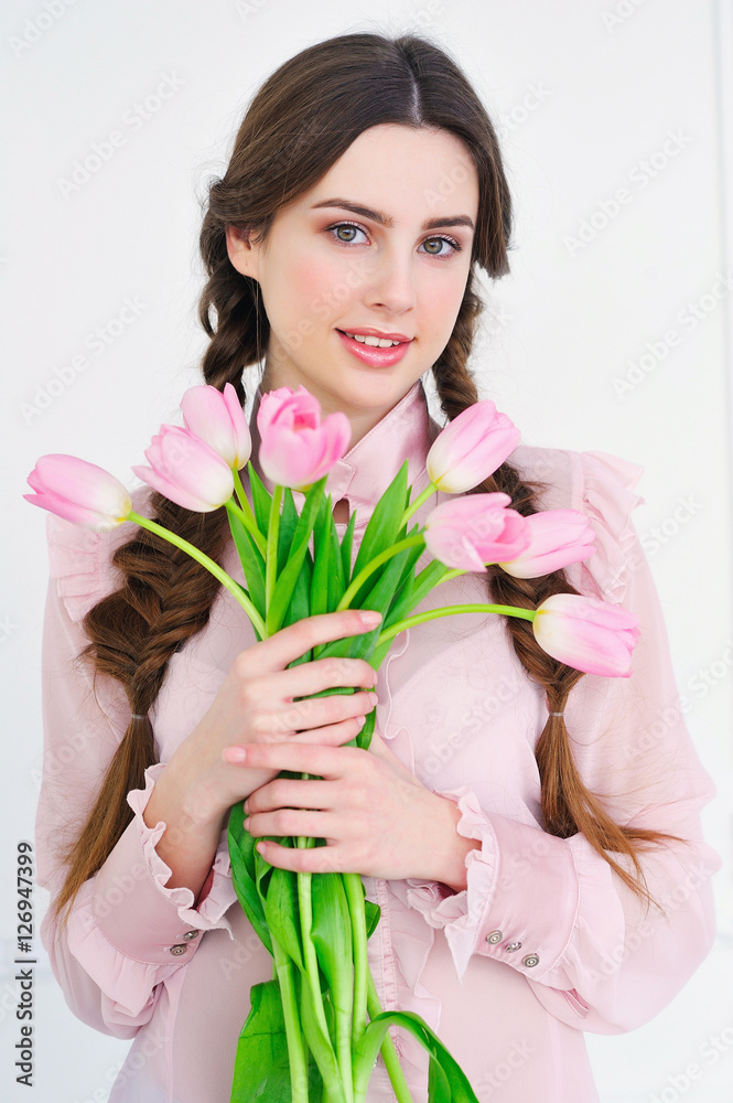 Beautiful young woman holding a bunch of delicate spring pink tulips in front of her Beautiful young woman holding a bunch of delicate spring pink tulips in front of her