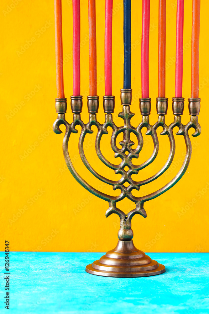 Fototapeta premium Hanukkah menorah with candles on the yellow background vertical