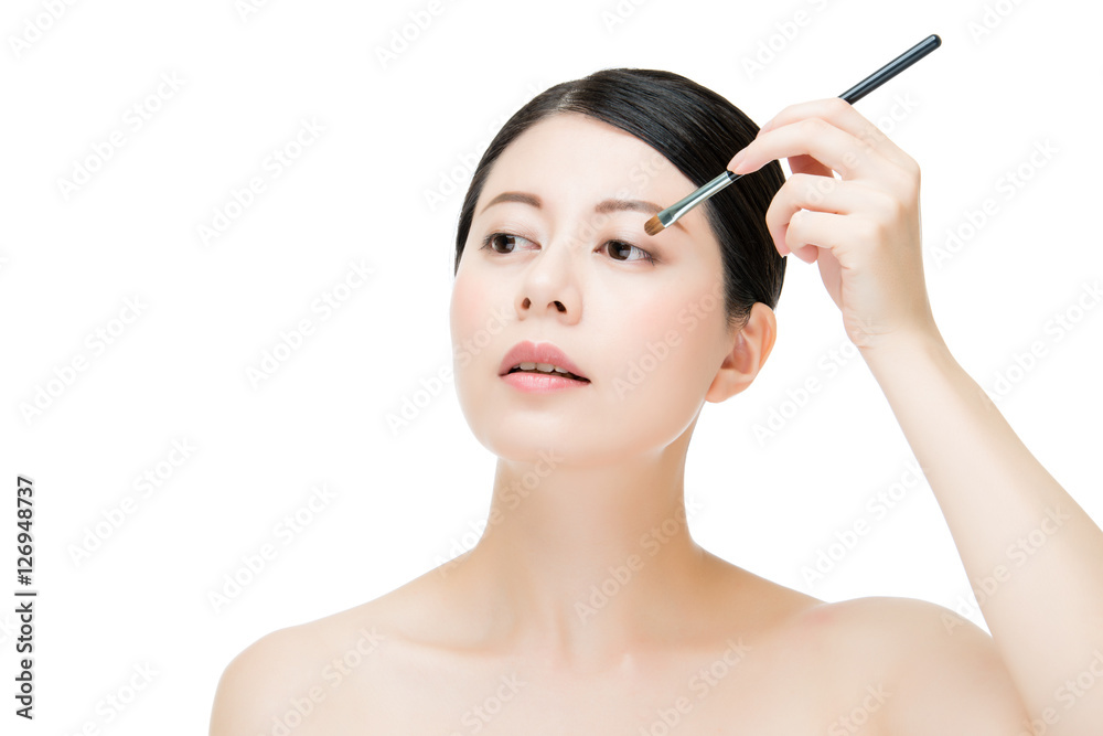 woman applying eyeshadow with makeup brush. asian beauty concept