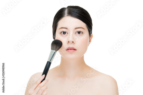 Beautiful young woman applying foundation powder blush with make