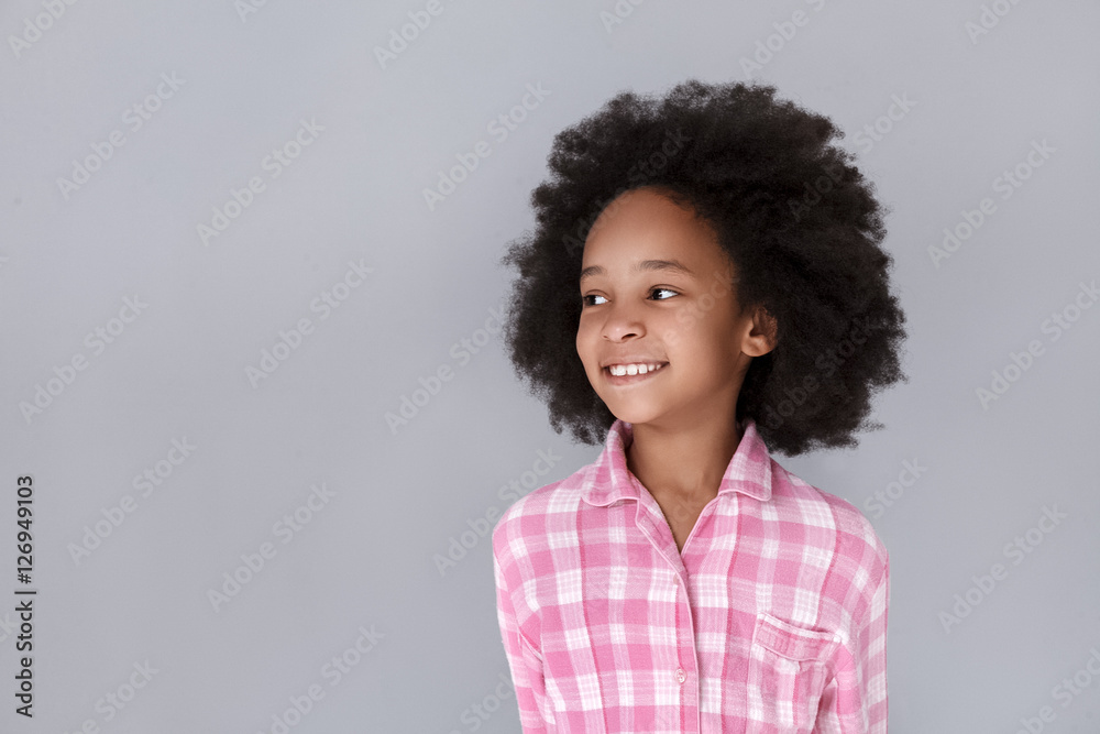 © dream_stock - Portrait of cheerful little girl looking away and smiling while standing against grey background © dream_stock - Portrait of cheerful little girl looking away and smiling while standing against grey background