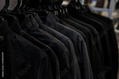 Black shirt hanging on a rack in the store. Fashion and garment