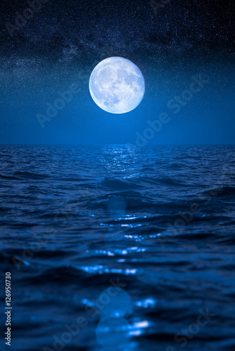 Full moon rising over empty ocean at night