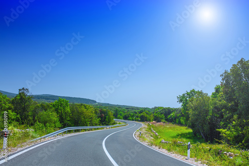 Beautiful asphalt freeway, motorway, highway without traffic through of southern landscape mountains forest during summer on a sunny day. Travel road concept. © Sodel Vladyslav
