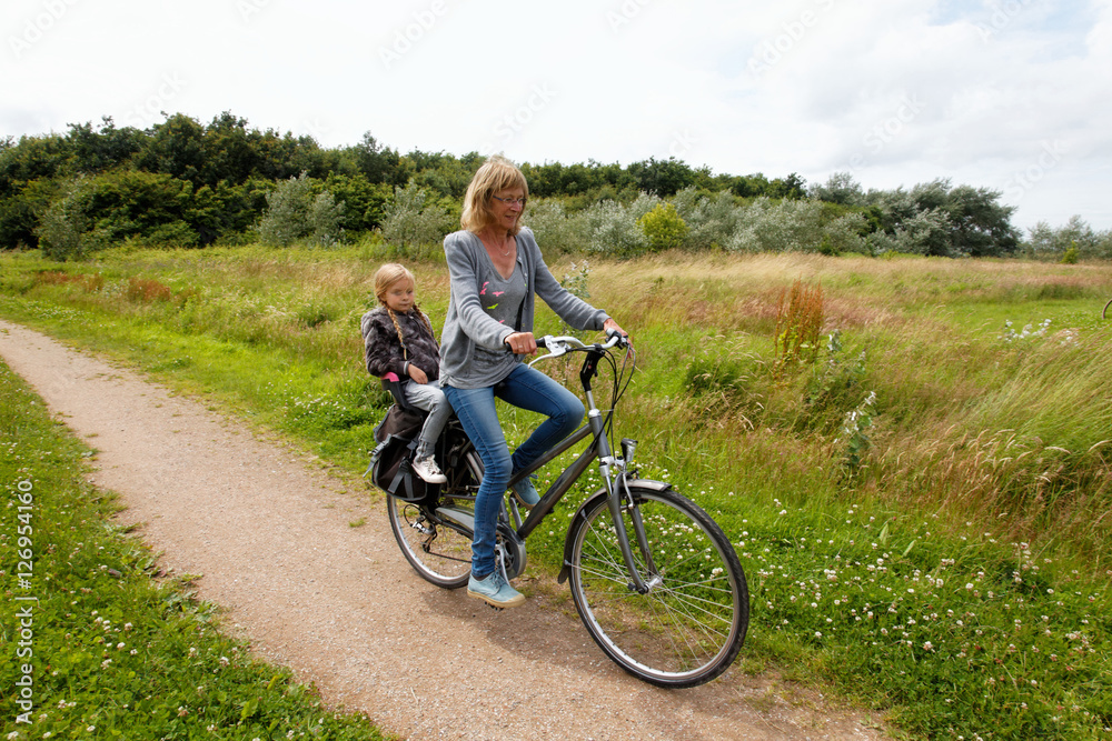 Happy woman and child cycling on a bike in nature