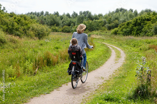 Woman with child on a bike cycling away in nature