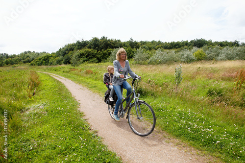 Happy woman on a bike with child behind bicycle