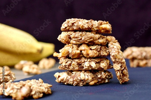 Banana cookies with walnuts and oats on dark background