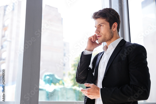 Businessman talking on mobile phone near the window in office