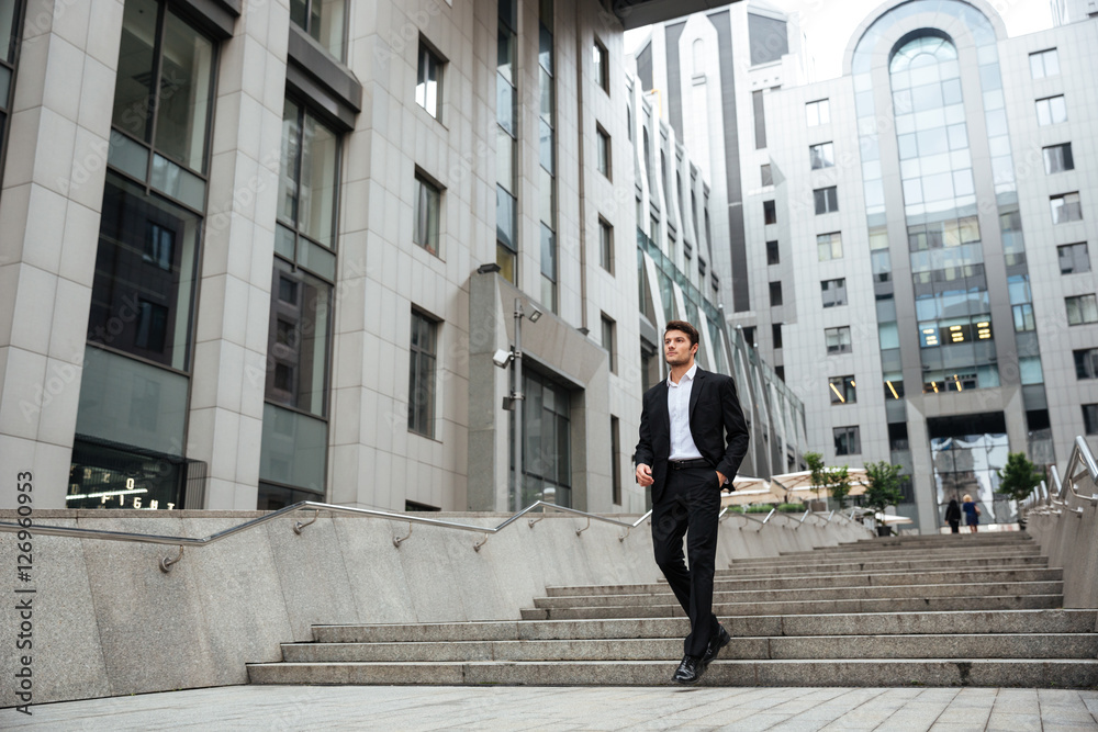 Businessman walking outdoors near business center Businessman walking outdoors near business center