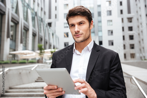 Pensive businessman using tablet in the city