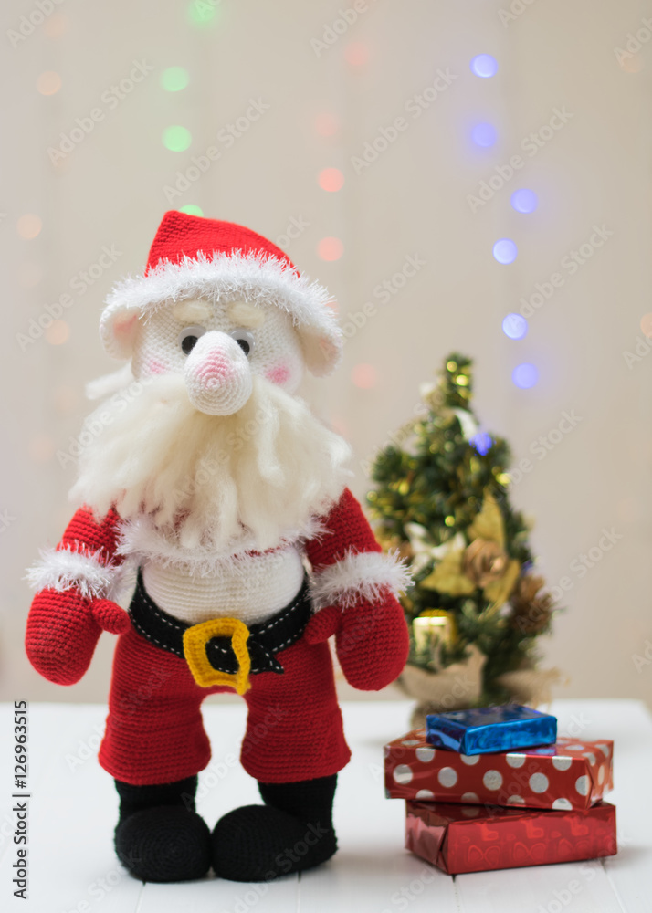 Knitted toy Santa Claus on a background of colorful bokeh.