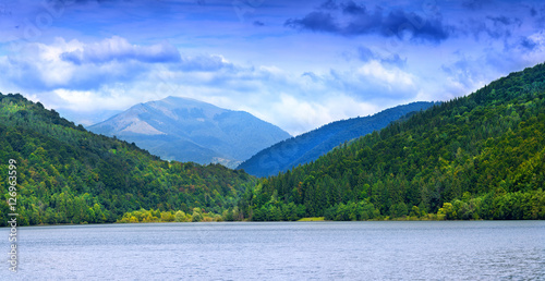 Panoramic view of beautiful lake and spruce forest in mountains at sunshine