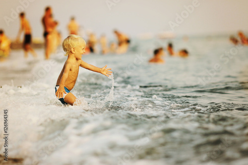 Kid plaing with wave in the sea photo