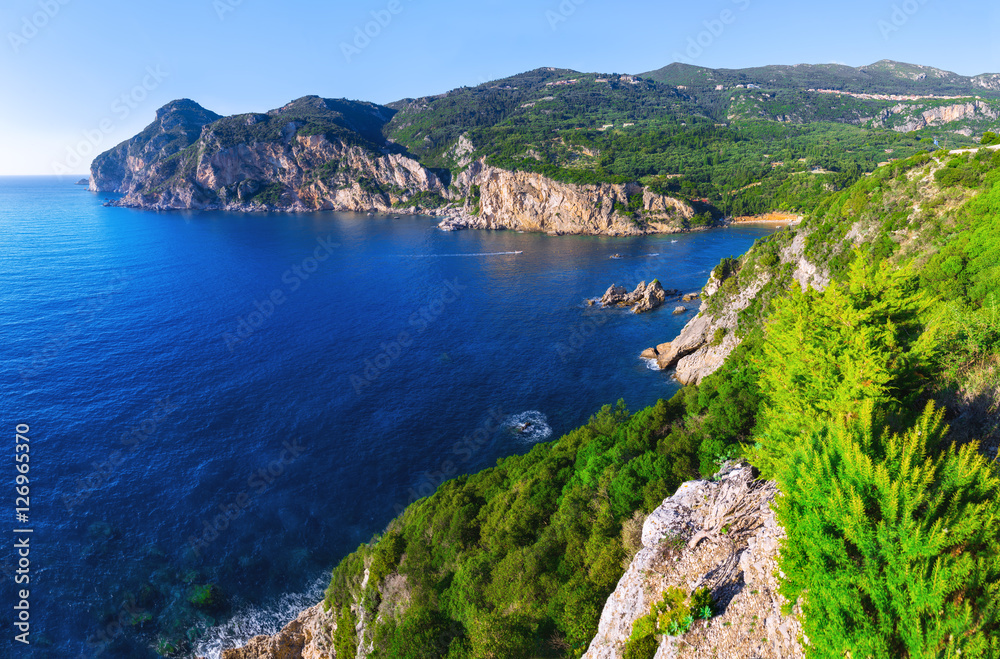 Fototapeta premium Landscape of Paleokastritsa famous beach in close bay with crystal clear azure water on Corfu island, Ionian archipelago, Greece.