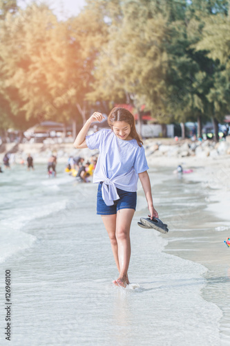 young woman standing at relax pose or freedom pose or chill pose on the beach in holiday. © chayantorn